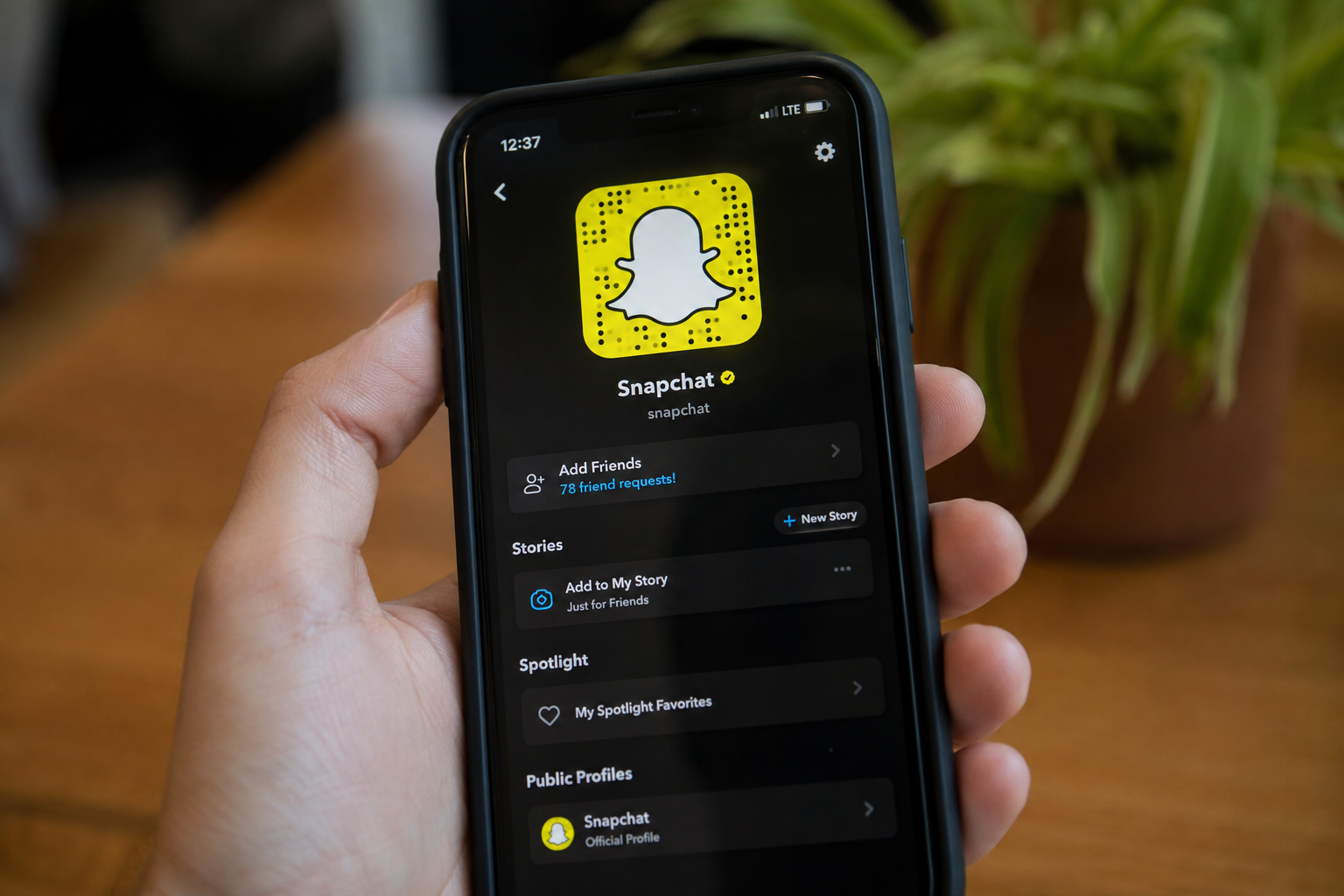 Eine Person hält ein Smartphone, auf dem die Snapchat-Profilseite und das bekannte gelbe Geist-Logo angezeigt werden.